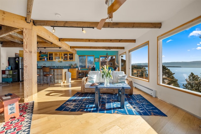 sunroom with wood finished floors, beamed ceiling, a water view, rail lighting, and a baseboard radiator