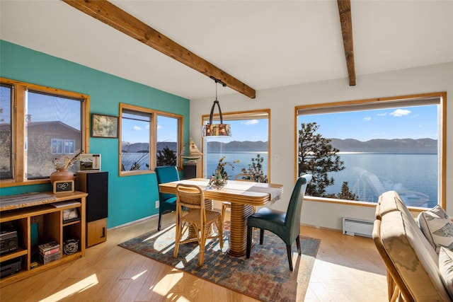 dining area featuring beam ceiling, a baseboard heating unit, a mountain view, and wood finished floors
