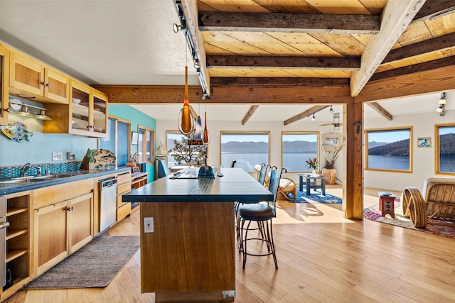 kitchen featuring a center island, a sink, dark countertops, and beamed ceiling
