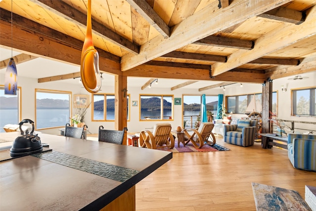 dining room with wooden ceiling, beamed ceiling, a water view, and light wood-type flooring
