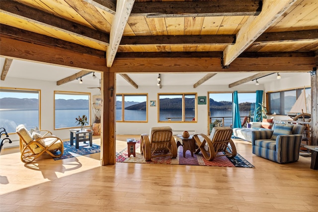 sunroom featuring track lighting, a water view, and beam ceiling