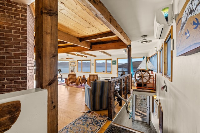 living room with brick wall, a wall mounted AC, wood finished floors, beamed ceiling, and a water view