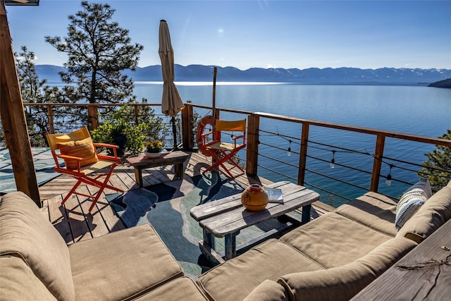 balcony with an outdoor living space and a water and mountain view
