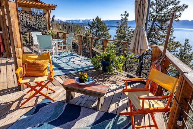 wooden terrace featuring outdoor dining area and a water and mountain view