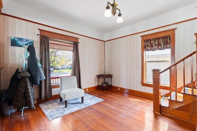 living area featuring wood-type flooring, stairs, and wallpapered walls