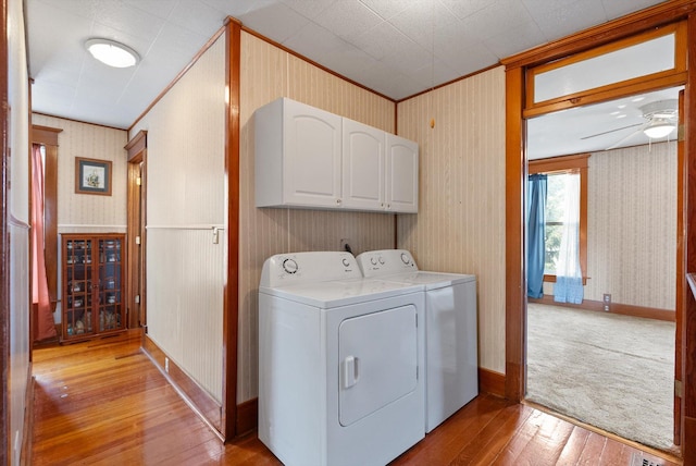 clothes washing area with cabinet space, wallpapered walls, crown molding, and light wood-type flooring