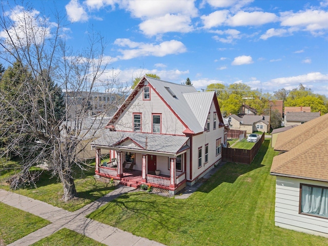view of front of house with covered porch, metal roof, and a front yard