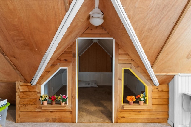 bonus room featuring carpet floors, wooden walls, and vaulted ceiling