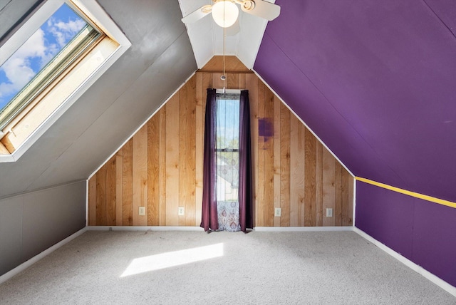 bonus room with carpet floors, ceiling fan, wood walls, and lofted ceiling