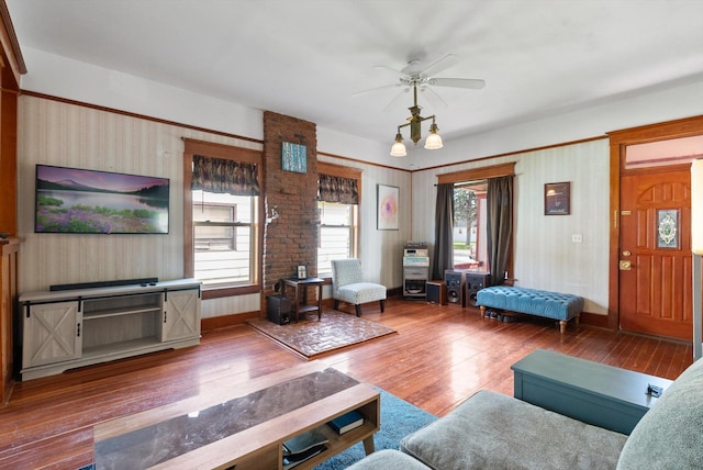 living area with baseboards, ceiling fan, and wood-type flooring