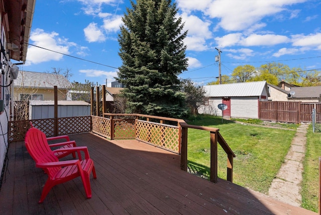 wooden deck with a lawn, fence, and an outdoor structure