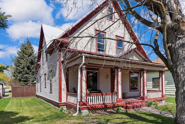 victorian-style house featuring covered porch and a front yard