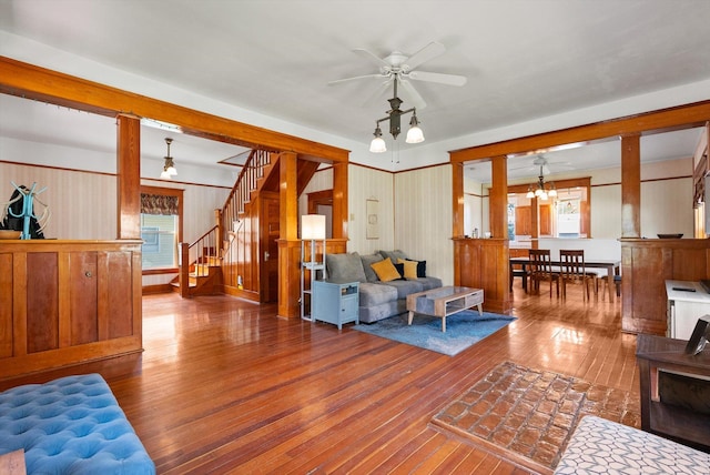 living room featuring stairway, ceiling fan, wood-type flooring, and wood walls