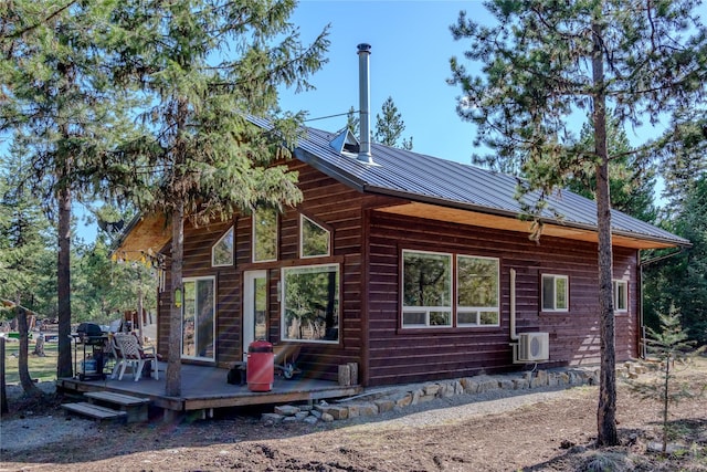 rear view of house featuring ac unit, a standing seam roof, a deck, and metal roof