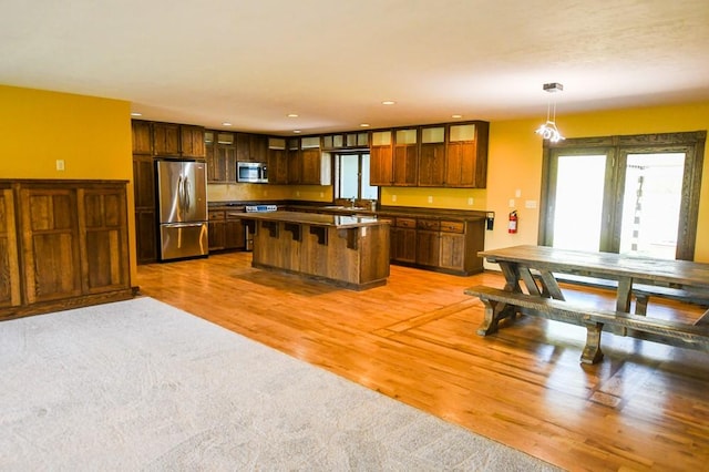 kitchen with a kitchen island, dark countertops, light wood-style floors, a sink, and stainless steel appliances
