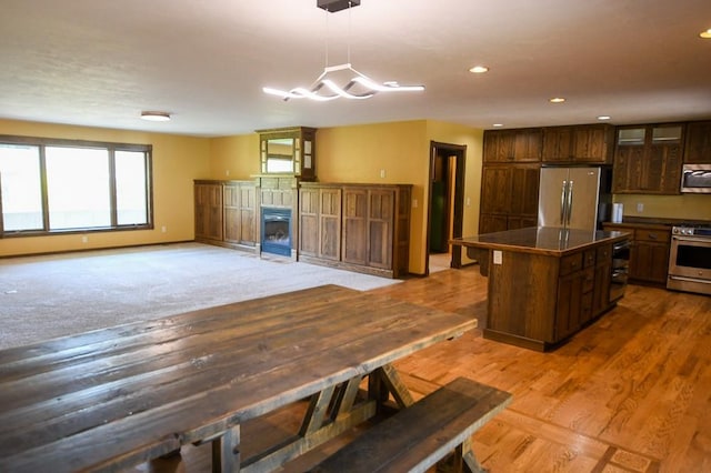 kitchen with a kitchen island, recessed lighting, dark countertops, and appliances with stainless steel finishes