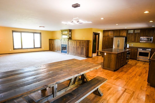 kitchen featuring dark countertops, appliances with stainless steel finishes, a center island, dark brown cabinets, and recessed lighting