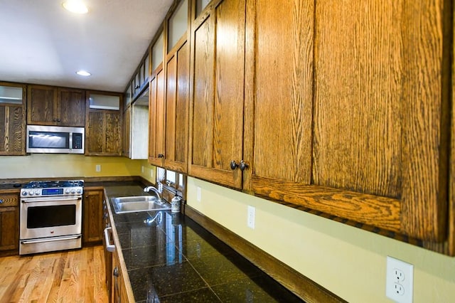 kitchen featuring glass insert cabinets, tile counters, recessed lighting, a sink, and stainless steel appliances