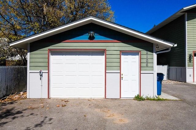 garage with fence and aphalt driveway