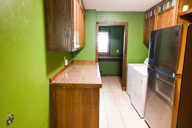 washroom featuring independent washer and dryer, light tile patterned flooring, and cabinet space
