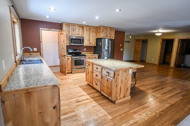 kitchen with a breakfast bar area, appliances with stainless steel finishes, light wood-type flooring, a sink, and recessed lighting