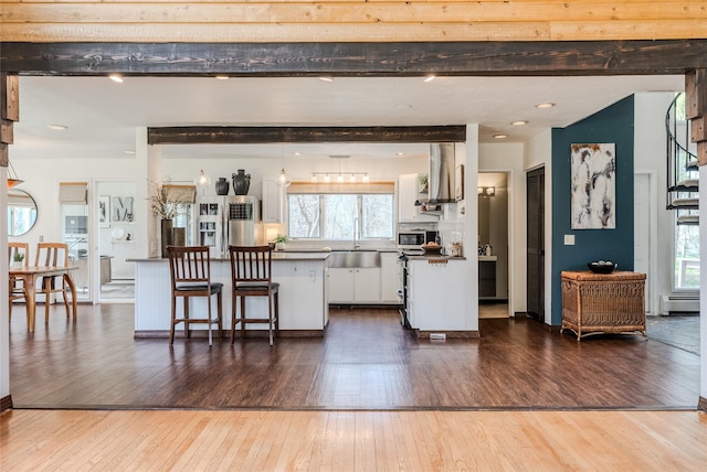 kitchen with dark wood-type flooring, white cabinetry, a baseboard heating unit, and a healthy amount of sunlight