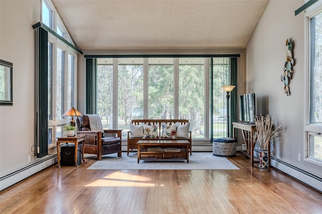 sunroom / solarium with a textured ceiling, baseboard heating, and hardwood / wood-style floors