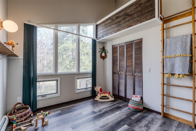 interior space with baseboards, a baseboard heating unit, and wood finished floors