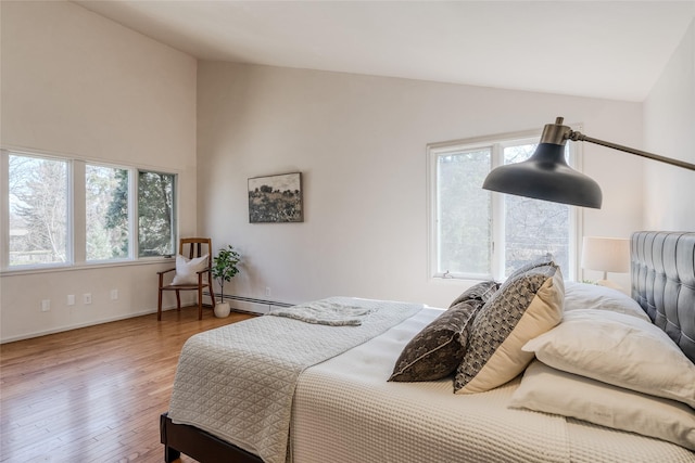 bedroom with wood-type flooring, baseboards, baseboard heating, and lofted ceiling