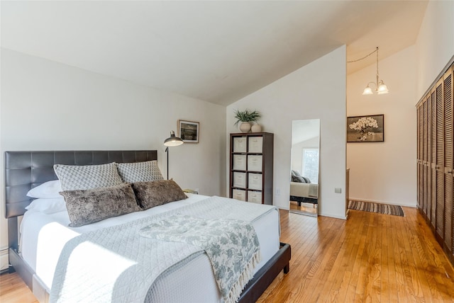 bedroom featuring a closet, light wood-style flooring, a chandelier, and high vaulted ceiling
