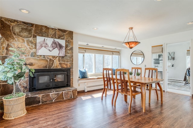 dining area featuring baseboard heating, a fireplace, recessed lighting, wood finished floors, and a baseboard heating unit