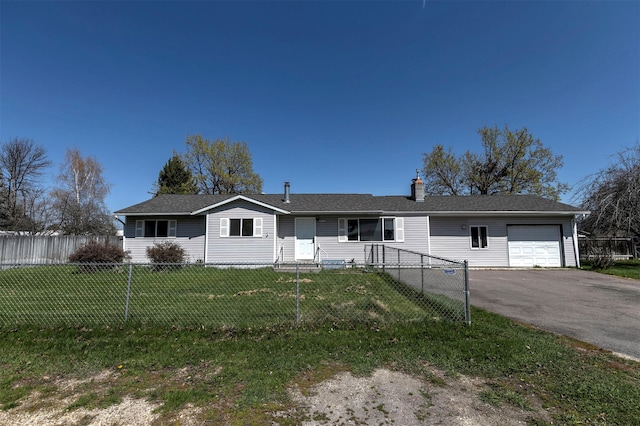 ranch-style home featuring a garage, a fenced front yard, a front yard, and aphalt driveway