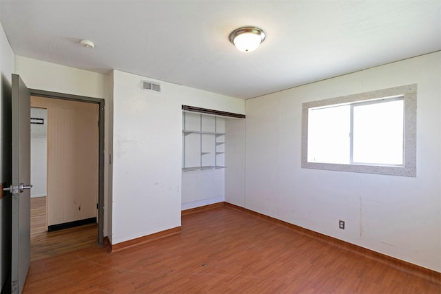 unfurnished room with baseboards, wood finished floors, and visible vents