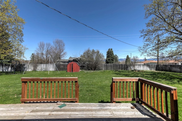 deck featuring a lawn, a fenced backyard, and a shed