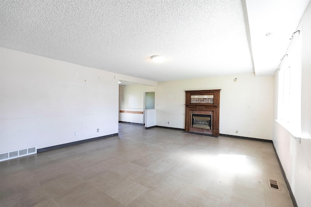 unfurnished living room with tile patterned floors, a textured ceiling, and visible vents