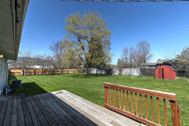 deck featuring a storage shed, a lawn, an outdoor structure, and a fenced backyard