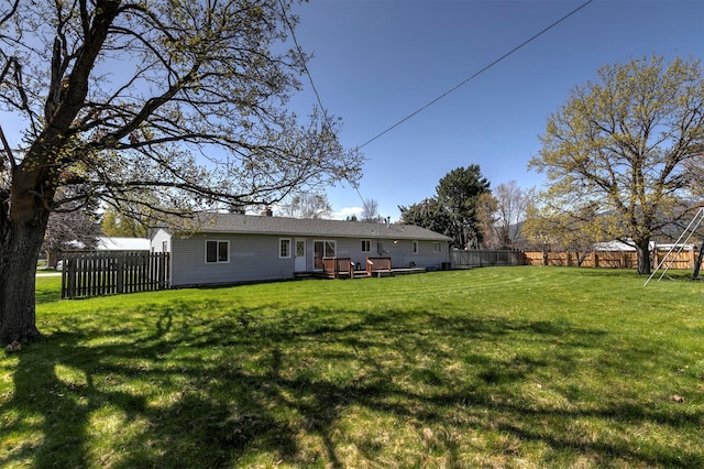 rear view of house featuring a lawn, a fenced backyard, and a wooden deck