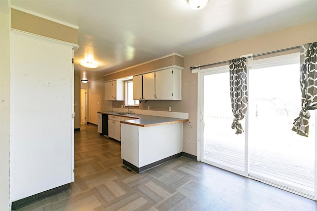 kitchen featuring a sink, dishwashing machine, a peninsula, and a healthy amount of sunlight