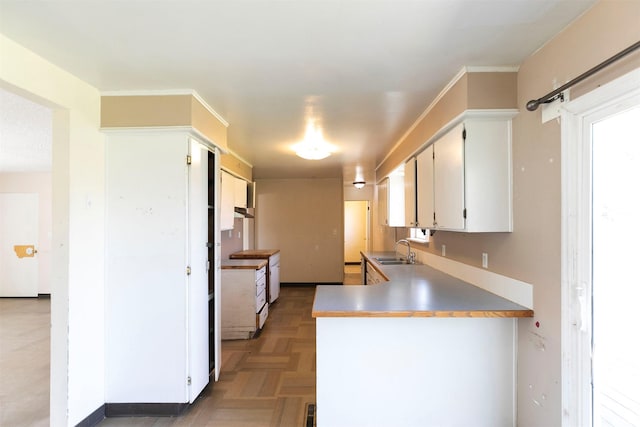 kitchen with a sink, a peninsula, and white cabinetry
