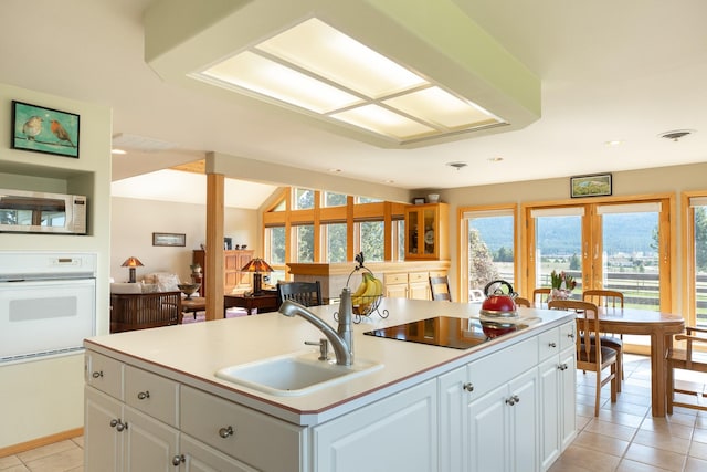 34051 Ridge Rd, Polson, MT 59860 - kitchen featuring black electric cooktop, light tile patterned floors, a sink, stainless steel microwave, and oven