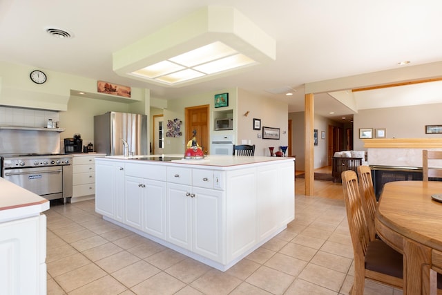 34051 Ridge Rd, Polson, MT 59860 - kitchen with light tile patterned flooring, a center island with sink, light countertops, white cabinetry, and stainless steel appliances