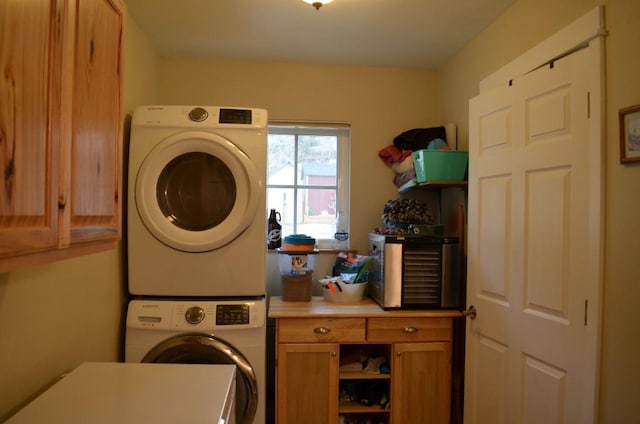 clothes washing area featuring cabinet space and stacked washer / dryer