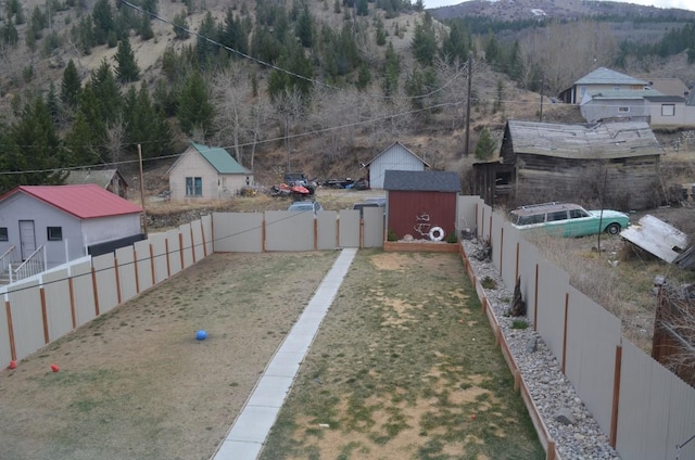 view of yard with a fenced backyard, a mountain view, an outbuilding, and a shed
