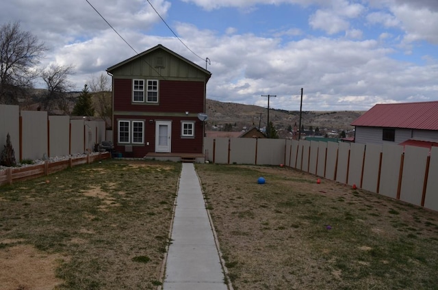 rear view of property featuring a fenced backyard, board and batten siding, and a yard