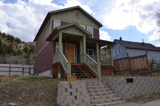 view of front facade with a porch, fence, and board and batten siding