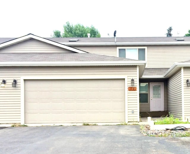 multi unit property featuring an attached garage and aphalt driveway