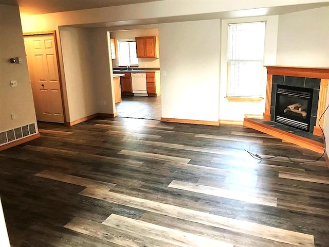 unfurnished living room featuring visible vents, baseboards, dark wood-type flooring, and a fireplace