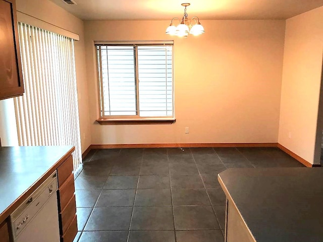 unfurnished dining area featuring dark tile patterned flooring, baseboards, and a notable chandelier