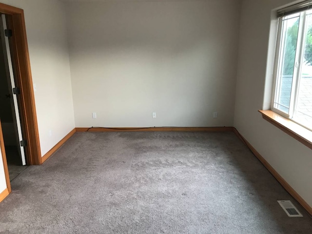 spare room featuring carpet floors, baseboards, and visible vents
