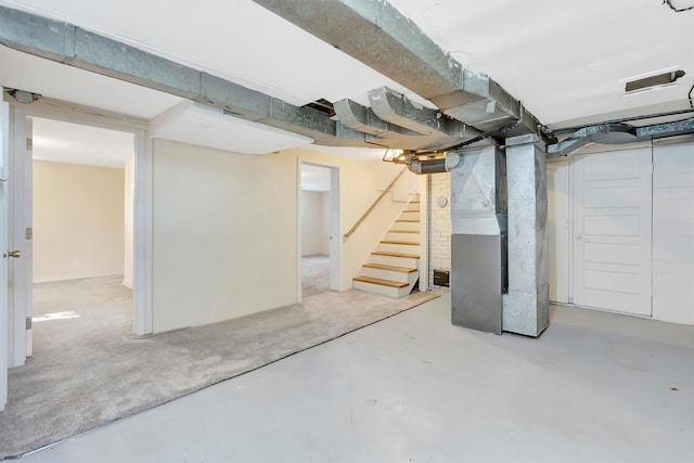 unfinished below grade area featuring heating unit and stairway